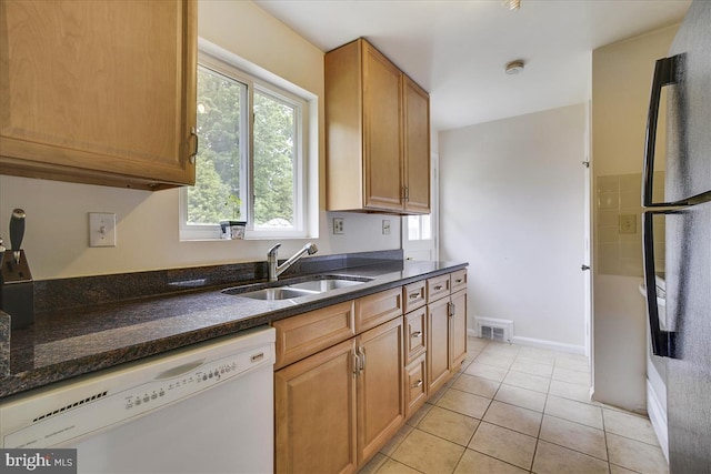 kitchen featuring visible vents, freestanding refrigerator, dark stone counters, a sink, and dishwasher