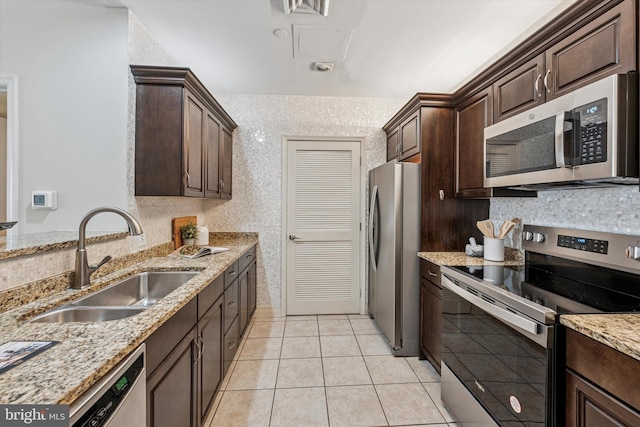 1600 Arch St Unit 1706, Philadelphia, PA 19103 - kitchen with a sink, light stone counters, dark brown cabinetry, light tile patterned floors, and appliances with stainless steel finishes
