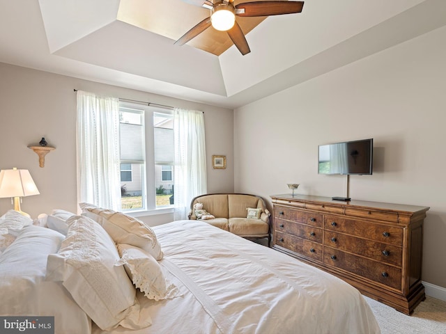 bedroom with a ceiling fan, a tray ceiling, and carpet
