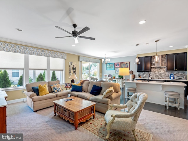 living area with crown molding, a toaster, ceiling fan with notable chandelier, and recessed lighting