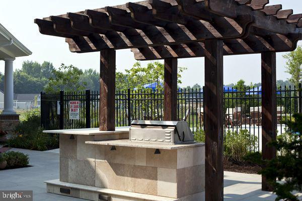 view of patio / terrace featuring fence, a pergola, and exterior kitchen