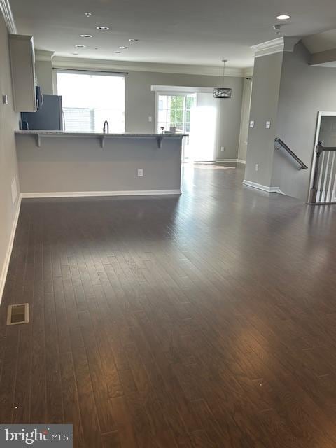 interior space with dark wood-style flooring, crown molding, baseboards, and visible vents