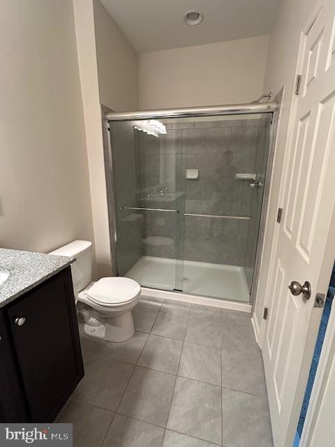 full bath with tile patterned floors, a shower stall, toilet, and vanity
