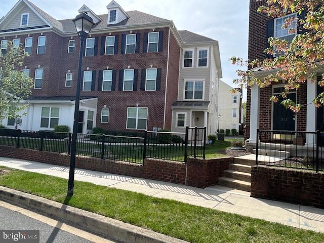 townhome / multi-family property featuring fence private yard and brick siding