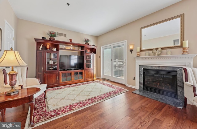living area with baseboards, wood finished floors, and a premium fireplace