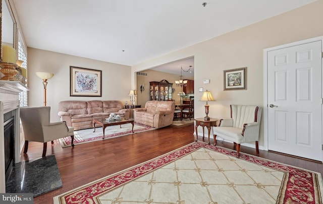 living area featuring visible vents, wood finished floors, a notable chandelier, and a fireplace