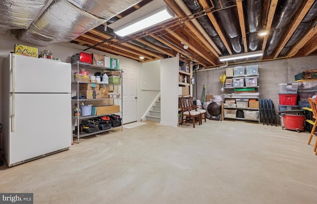 unfinished below grade area with freestanding refrigerator and stairs