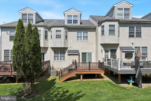back of property with central air condition unit, stucco siding, a yard, and a deck