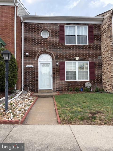 multi unit property featuring brick siding and a front lawn