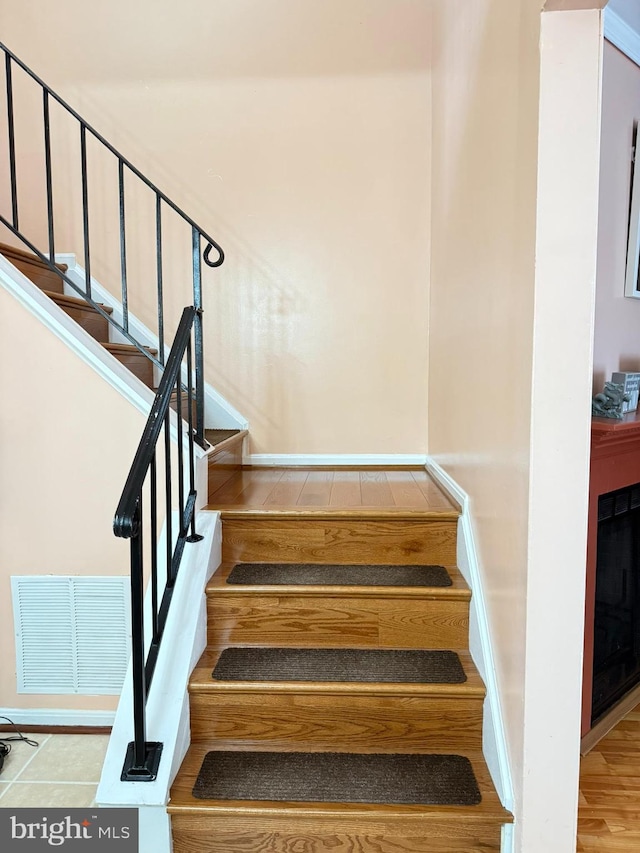 stairway featuring baseboards, visible vents, and tile patterned flooring