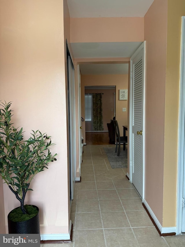 hallway with light tile patterned floors and baseboards