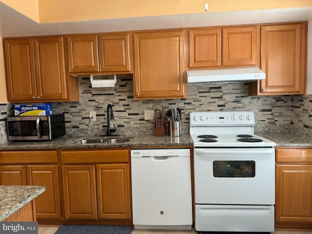 kitchen featuring white appliances, under cabinet range hood, decorative backsplash, and a sink