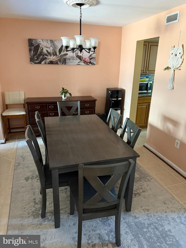 dining area with light tile patterned flooring, a notable chandelier, visible vents, and baseboards