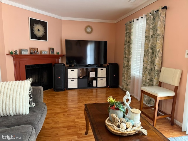 living area featuring baseboards, ornamental molding, a fireplace, and light wood-type flooring