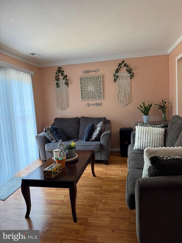 living room with crown molding, visible vents, and light wood-type flooring