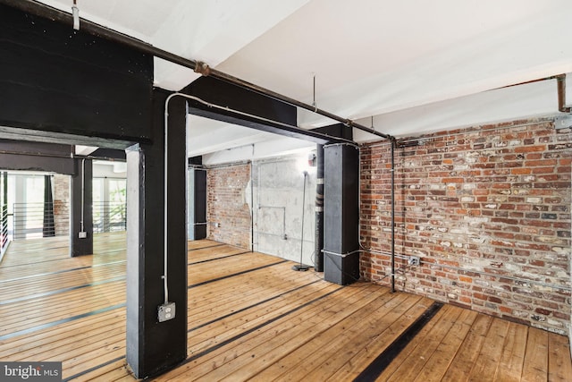 interior space with brick wall and wood-type flooring