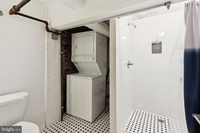 full bathroom with a stall shower, toilet, tile patterned floors, and stacked washer / dryer