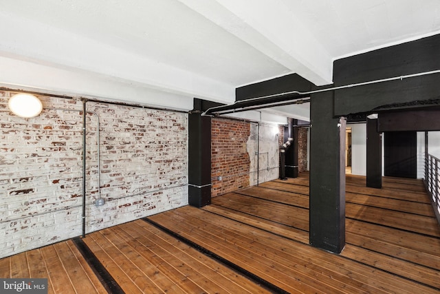 basement with brick wall and wood-type flooring
