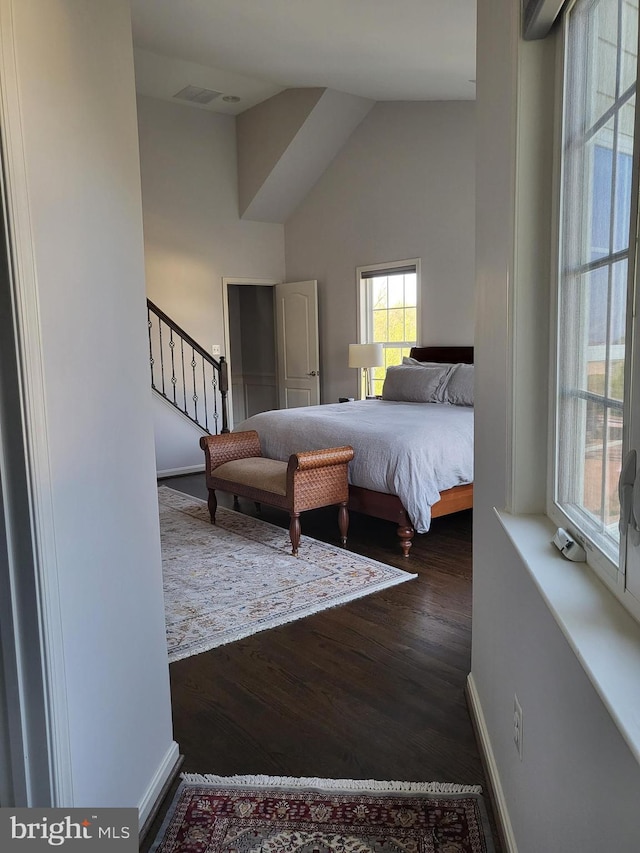 bedroom featuring high vaulted ceiling, visible vents, and wood finished floors