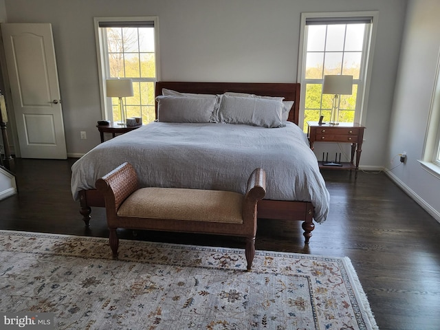 bedroom featuring baseboards, multiple windows, and wood finished floors