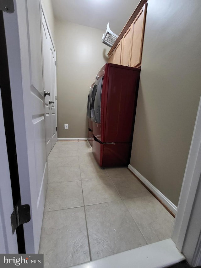 clothes washing area featuring baseboards, cabinet space, and washing machine and dryer