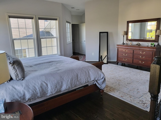bedroom with baseboards, multiple windows, wood finished floors, and visible vents