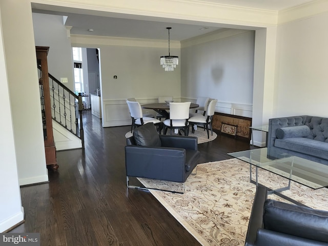 living room with stairs, a chandelier, ornamental molding, and wood finished floors