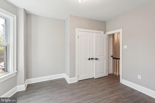 unfurnished bedroom with a closet, wood finished floors, and baseboards