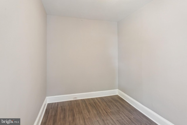 spare room with baseboards and dark wood finished floors