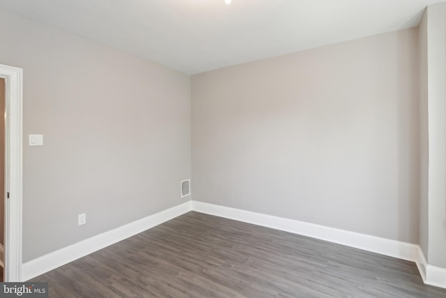 empty room with baseboards, dark wood-style floors, and visible vents