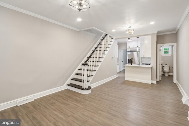 unfurnished living room with ornamental molding, stairway, visible vents, and wood finished floors