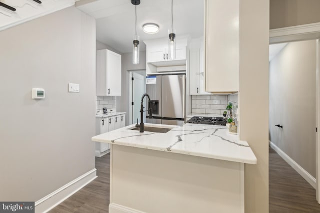 kitchen with a peninsula, stainless steel fridge, dark wood finished floors, decorative backsplash, and light stone counters
