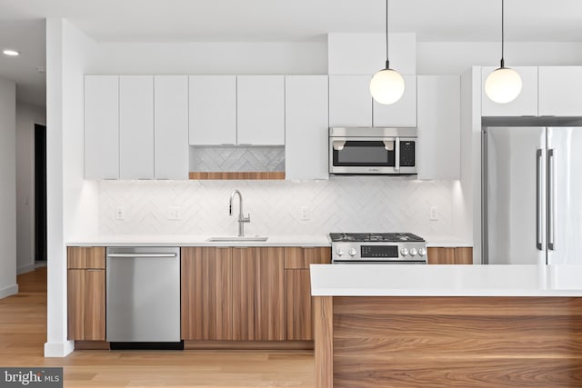 kitchen featuring white cabinetry, appliances with stainless steel finishes, a sink, and modern cabinets