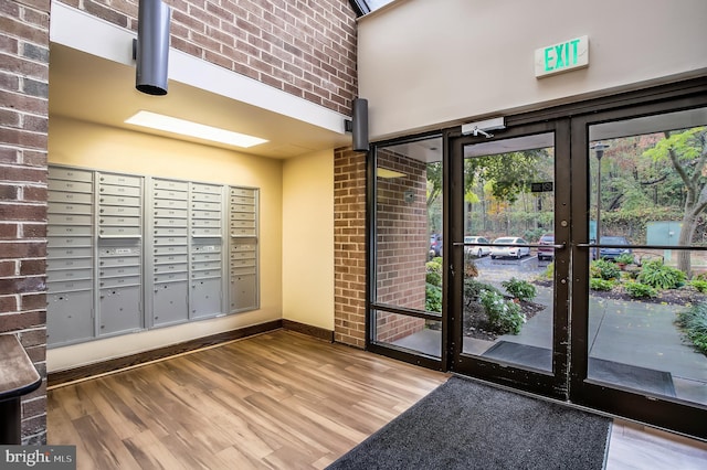 3 Southerly Ct Unit 602, Towson, MD 21286 - doorway featuring mail area, wood finished floors, a high ceiling, brick wall, and baseboards