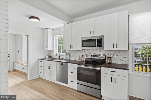 kitchen with appliances with stainless steel finishes, a sink, dark countertops, and decorative backsplash
