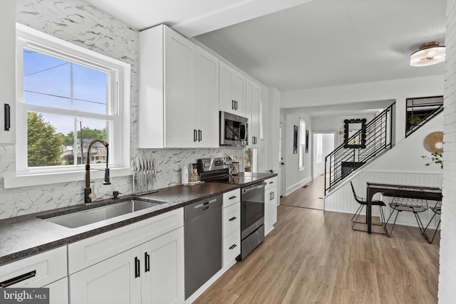 kitchen featuring appliances with stainless steel finishes, a sink, dark countertops, and tasteful backsplash