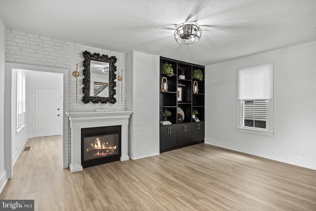 unfurnished living room with wood finished floors, a glass covered fireplace, and baseboards