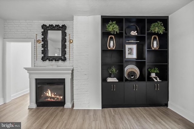 detailed view of wood finished floors, a fireplace, and baseboards