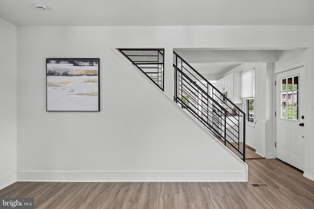 entrance foyer featuring baseboards, wood finished floors, and stairway