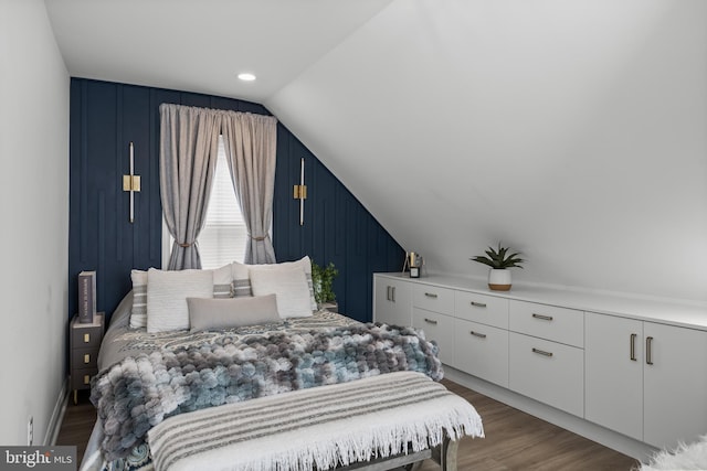bedroom with lofted ceiling, wood finished floors, baseboards, and wood walls