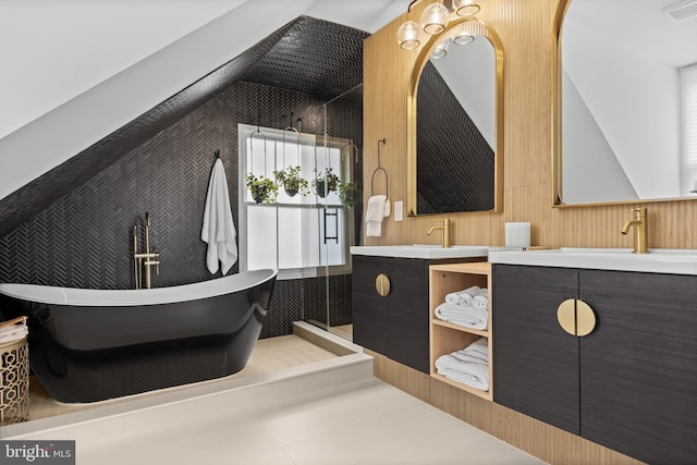 full bathroom with a stall shower, two vanities, a freestanding bath, lofted ceiling, and tile patterned flooring