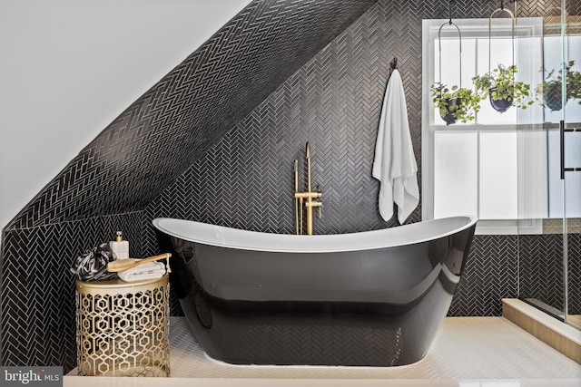 bathroom featuring tile walls, a soaking tub, and a stall shower