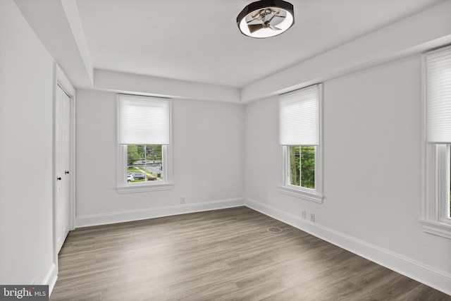 unfurnished bedroom with multiple windows, wood finished floors, and baseboards
