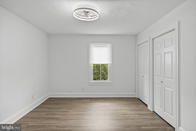 unfurnished bedroom with wood finished floors and baseboards