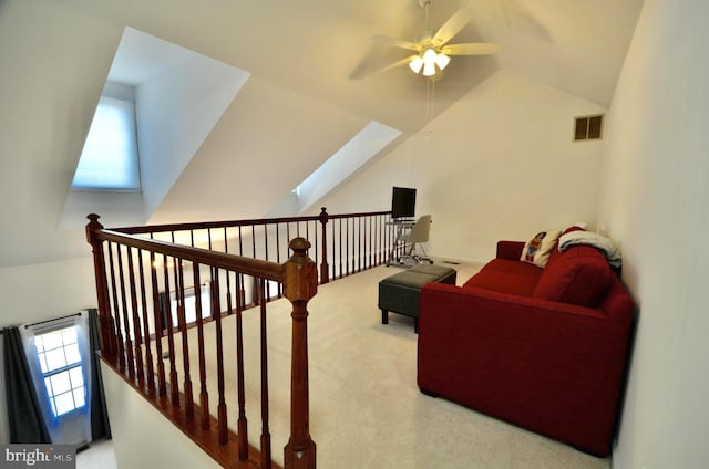 living area with vaulted ceiling with skylight, ceiling fan, visible vents, an upstairs landing, and carpet