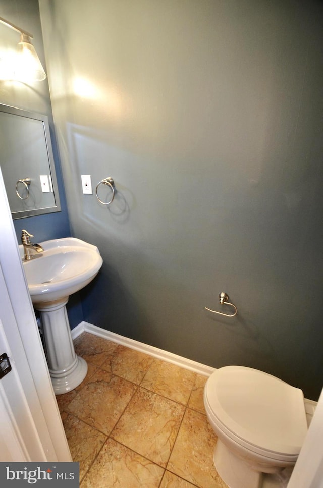 bathroom with toilet, baseboards, and stone tile flooring