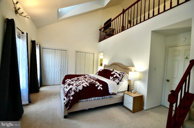 bedroom featuring carpet, multiple closets, a skylight, and high vaulted ceiling