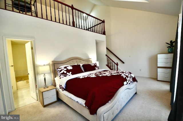 carpeted bedroom featuring a high ceiling and ensuite bath