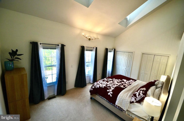 bedroom featuring multiple closets, visible vents, lofted ceiling with skylight, and carpet