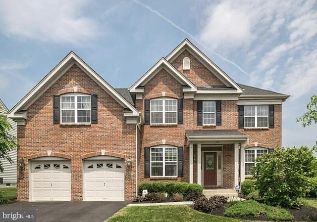view of front facade featuring driveway, brick siding, and an attached garage